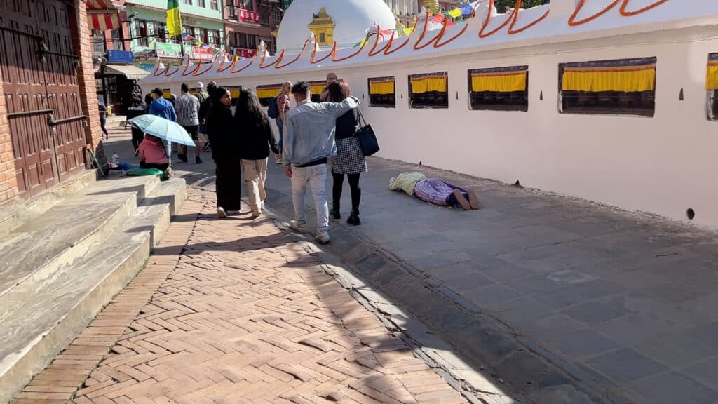 Gläubiger, Pilger der am Boden betet an dem Buddha Stupa in Kathmandu
